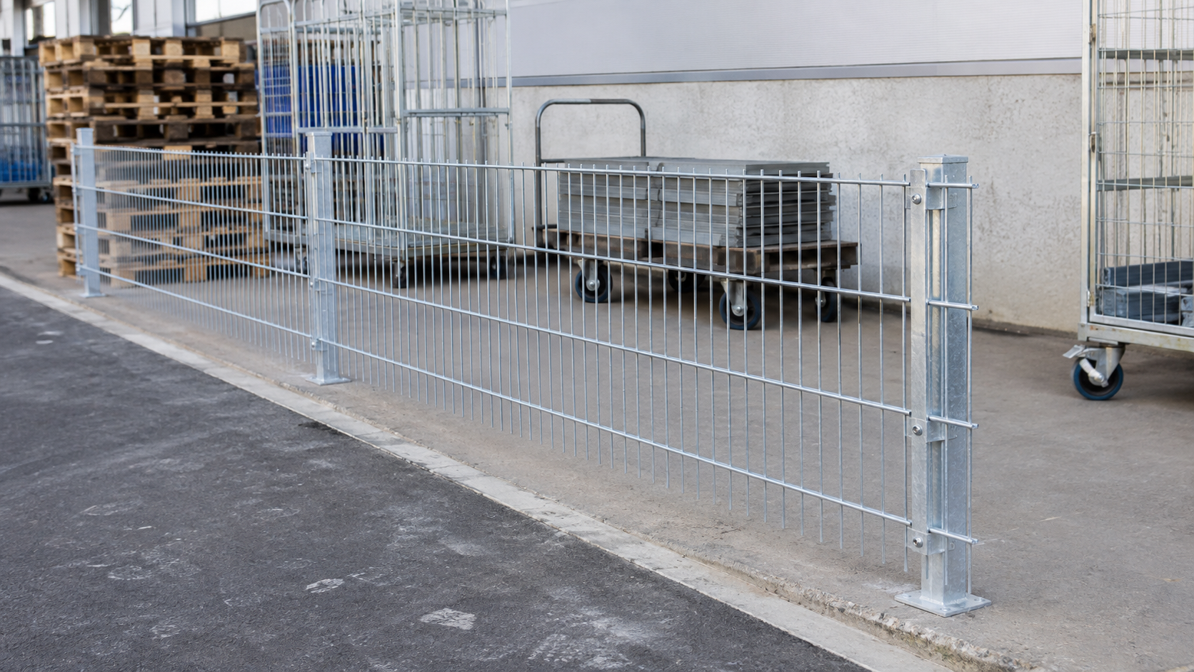 Verzinkter Doppelstabmattenzaun an einer Lagerfläche mit Paletten und Gewerbehof